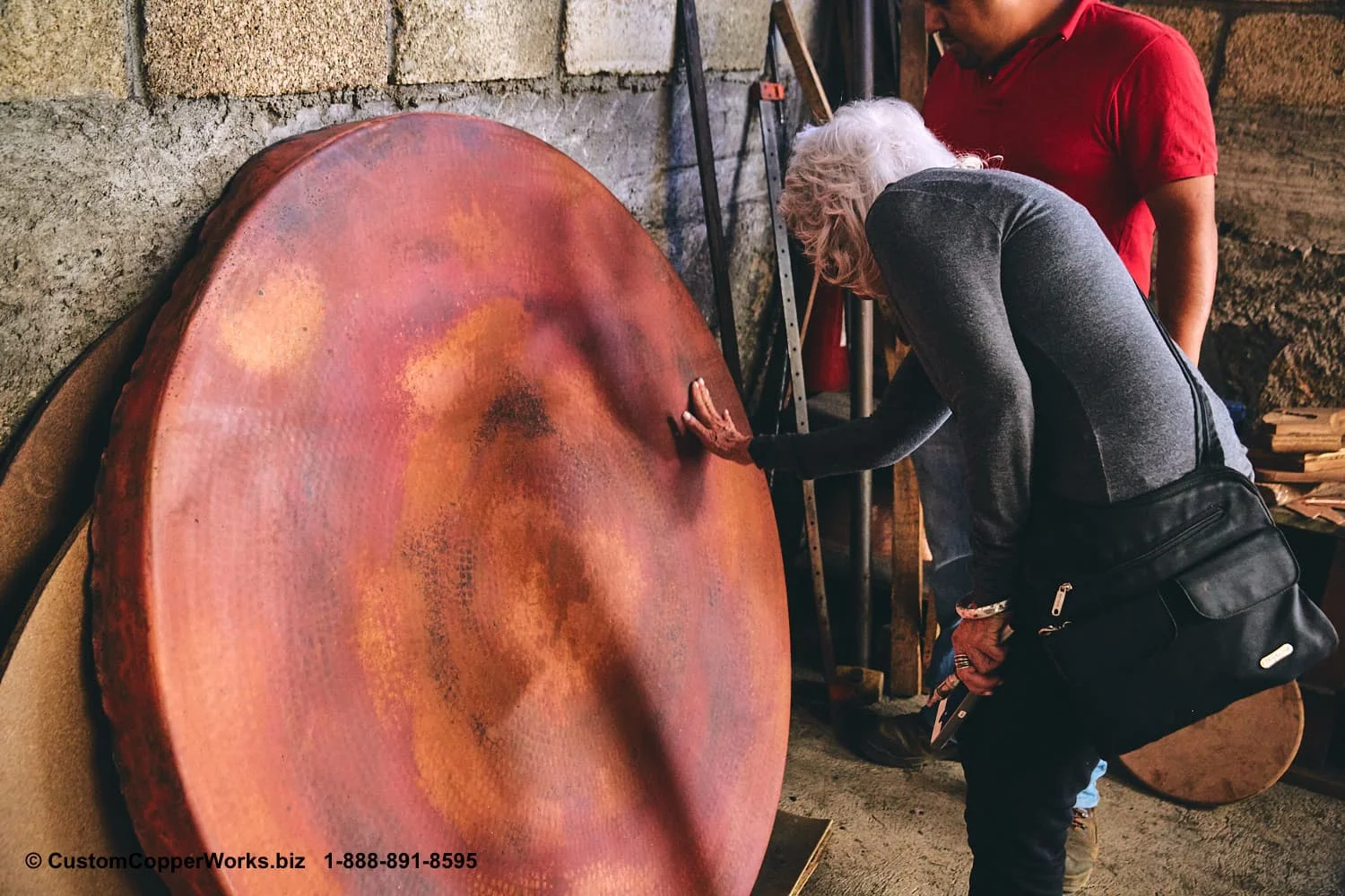Teresa checking the patina on a round copper top at the workshop in Mexico